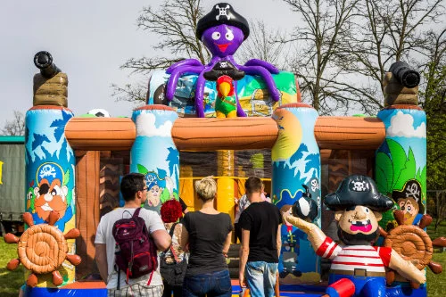 Besucher stehen vor einer Piratenhüpfburg mit einer lilafarbenen Oktopusfigur auf dem Dach.