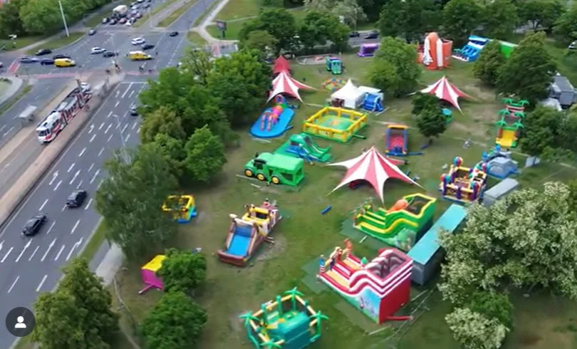 Luftaufnahme des gesamten Hüpfburgenparks mit zahlreichen bunten Hüpfburgen auf einer Grünfläche neben einer Straßenkreuzung in Cottbus.