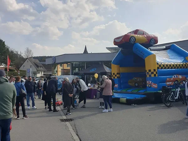 Hüpfburg mit Automotiv im Einsatz bei einem Straßenfest mit zahlreichen Besuchern.
